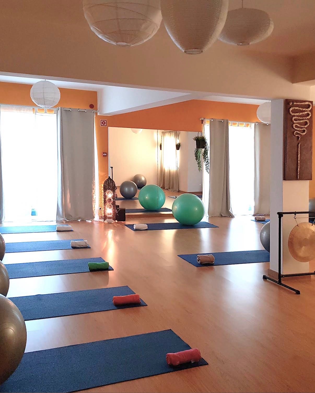 Studio with exercise mats, cushions, stability balls, and a mirrored wall